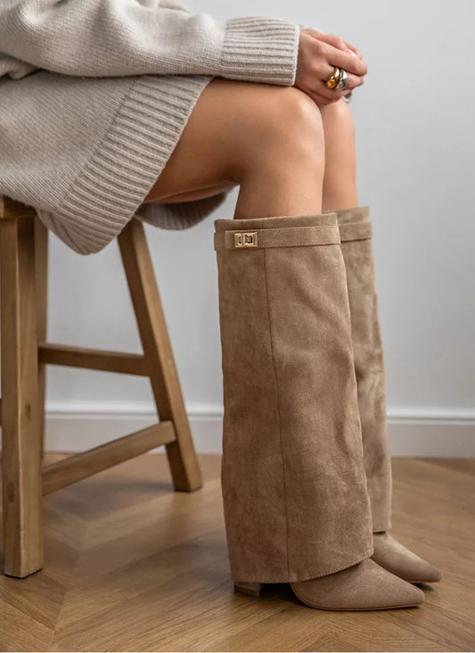 Person wearing tan knee-high boots sitting on a wooden stool.