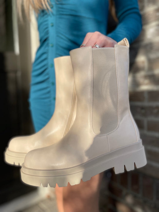 Beige rubber boots worn by a person in a blue outfit with a blurred background